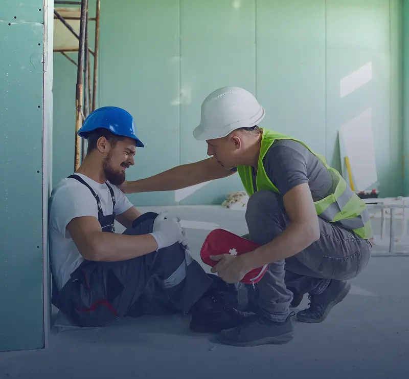 Worker assisting injured colleague on construction site.