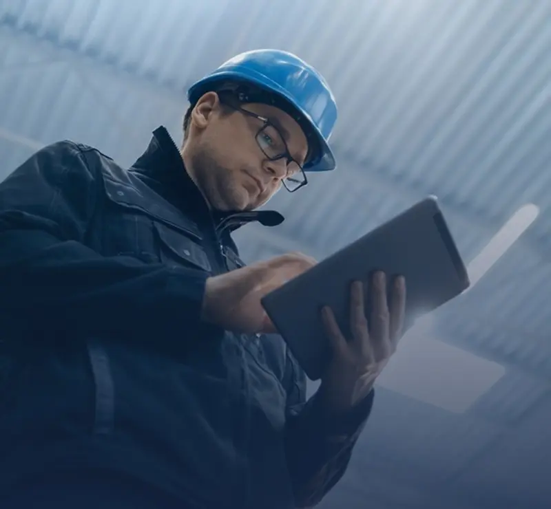 Man in hard hat using tablet.